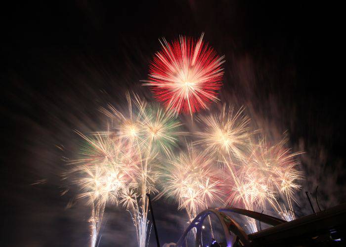 A firework display at the Toyota Oiden Fireworks Festival, with bright reds and golds against the night sky.